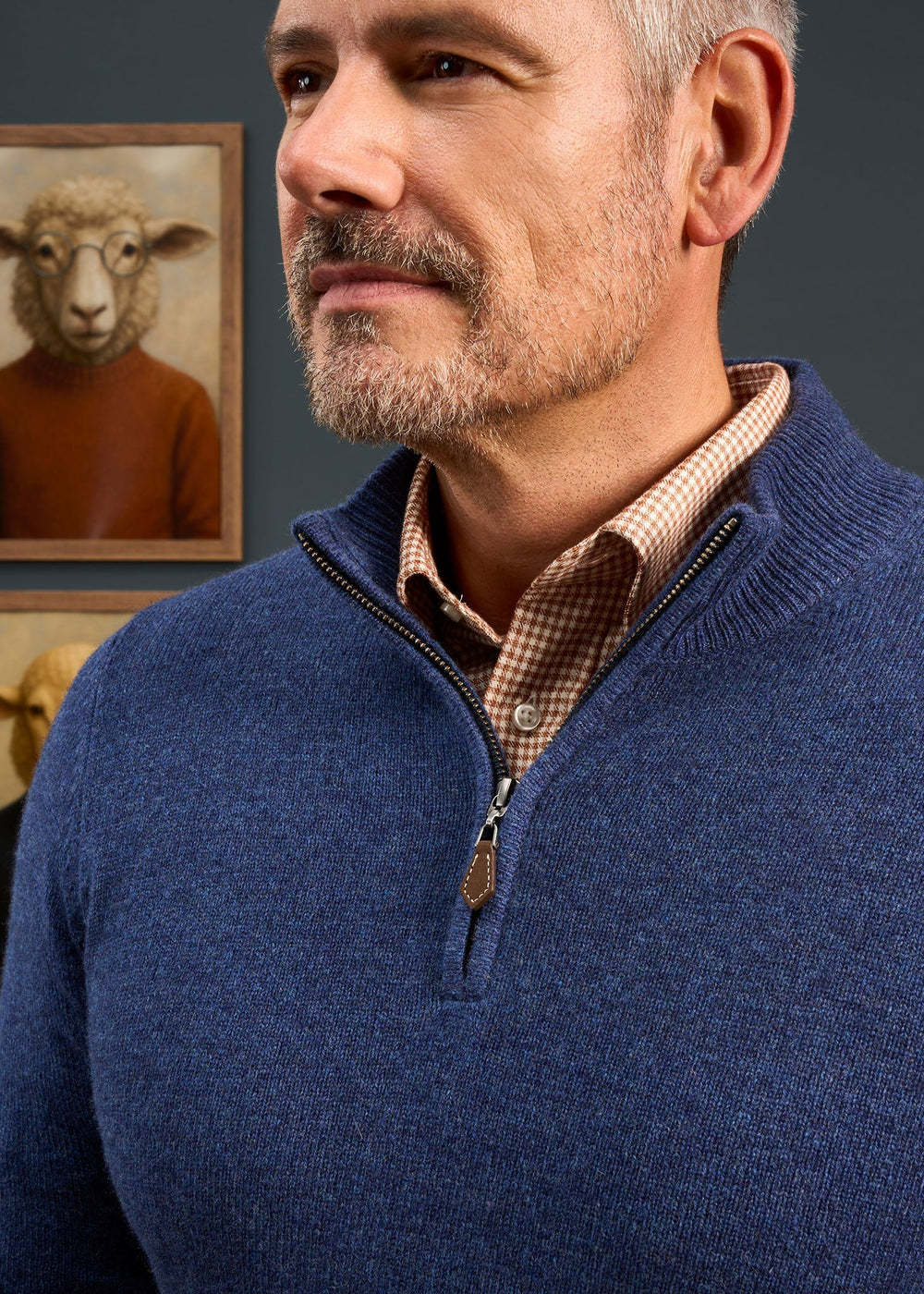 A man wearing a Sutherland Lambswool Quarter Zip Jumper In Rhapsody over a brown patterned shirt.