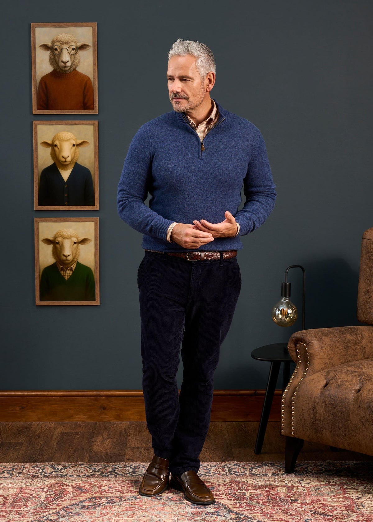 A man wearing a Sutherland Lambswool Quarter Zip Jumper In Rhapsody over a patterned collared shirt and dark trousers.