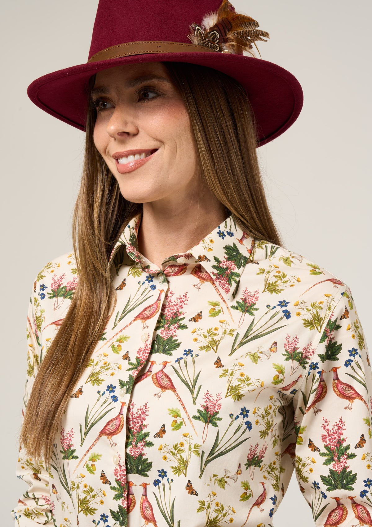 Woman in a maroon feathered hat wears the Lawen Cream Floral Cotton Printed Shirt, looking slightly to the side.