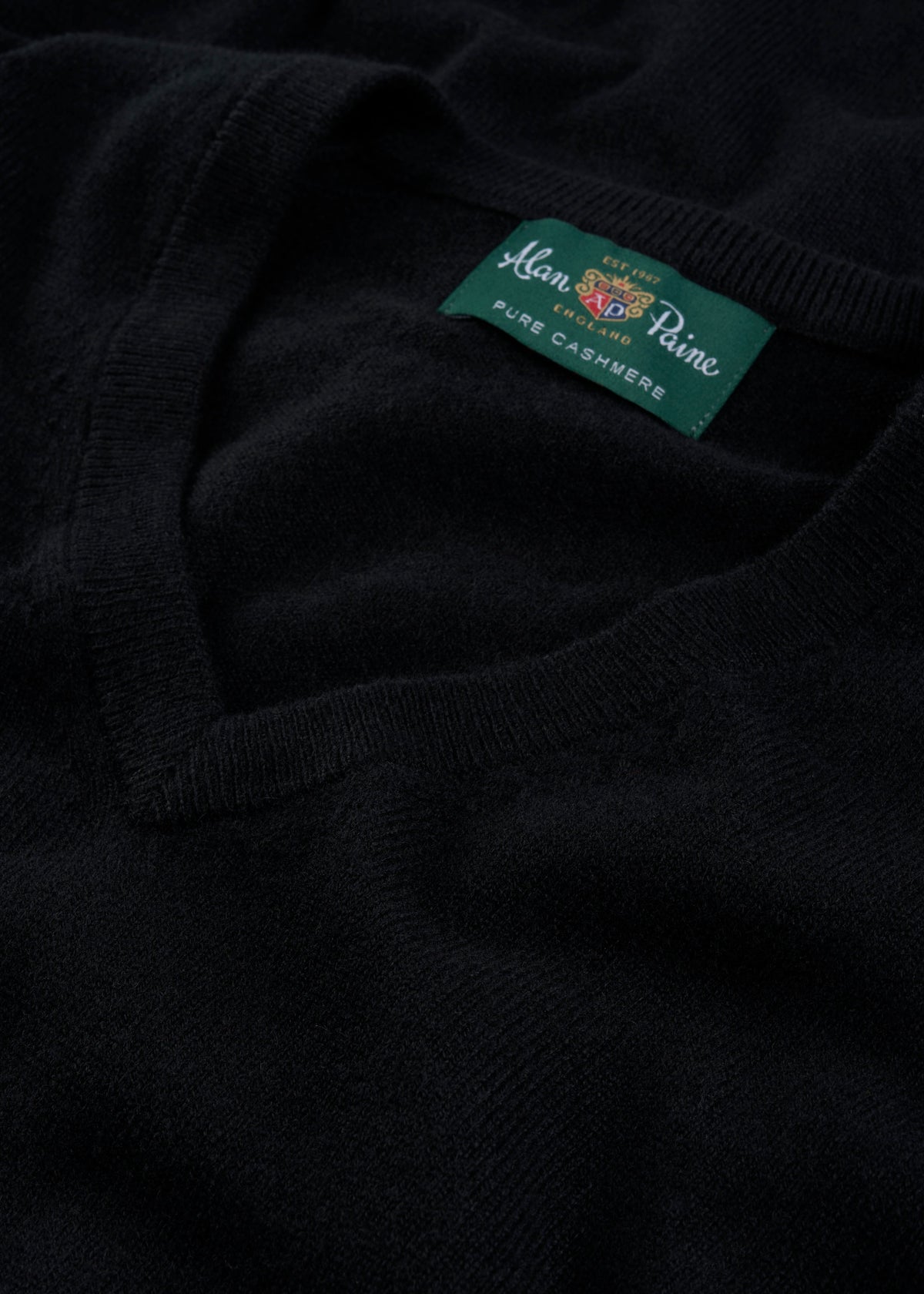 Close-up of a Haddington Pure Cashmere V-Neck Jumper in black, regular fit, with visible Alan Paine label.