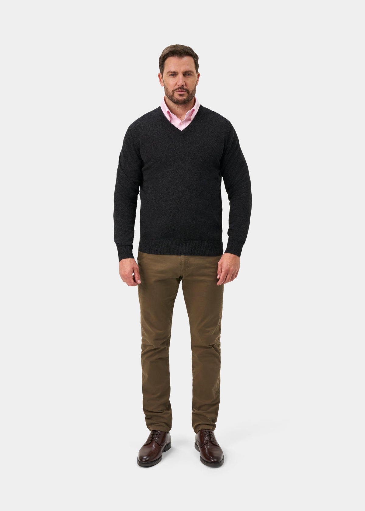 Man in a Haddington Pure Cashmere V-Neck Jumper in charcoal, pink shirt, brown pants, and shoes on white background.