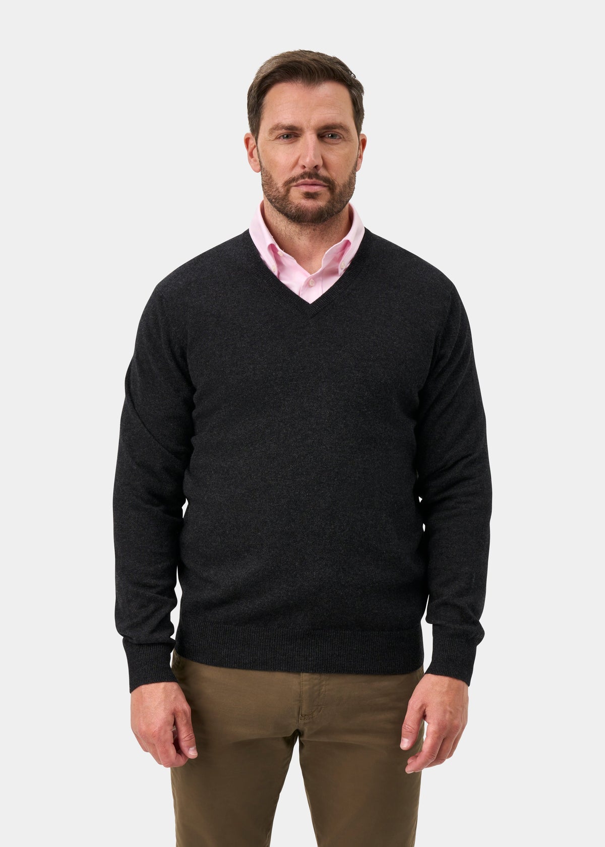 Man in Haddington Pure Cashmere V-Neck Jumper in charcoal, over a pink shirt and khakis, against a plain background.