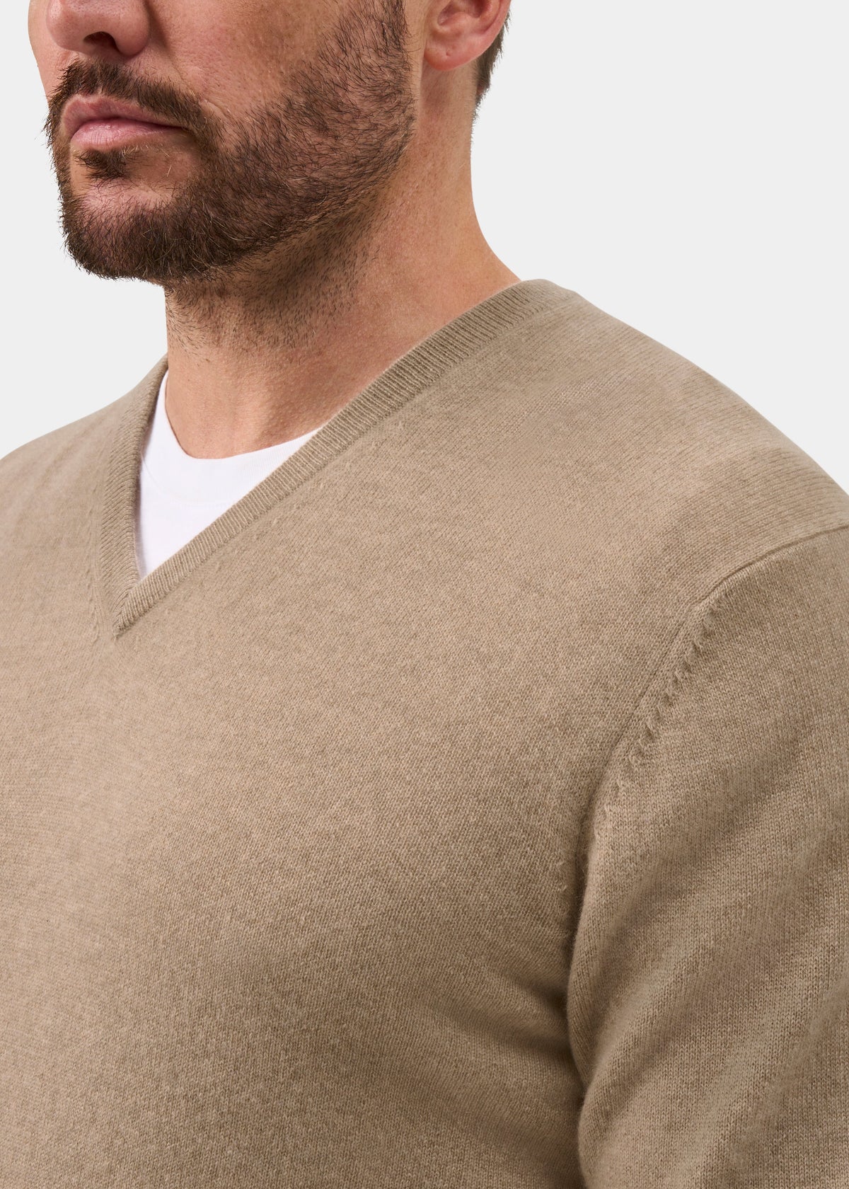 Man wearing Haddington Pure Cashmere V-Neck Jumper in Linen, regular fit, over a white shirt against plain background.