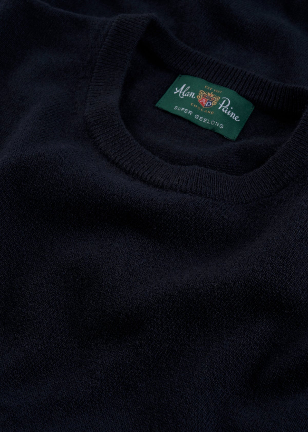 Close-up of a Brisbane Geelong Wool Crew Neck Jumper in Dark Navy - Regular Fit, featuring a green label.
