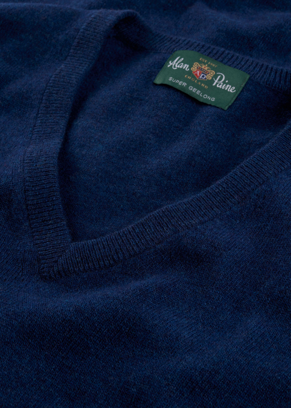 Close-up of Albury Geelong Wool V-Neck Jumper in indigo with visible V-neck and Alan Paine label.