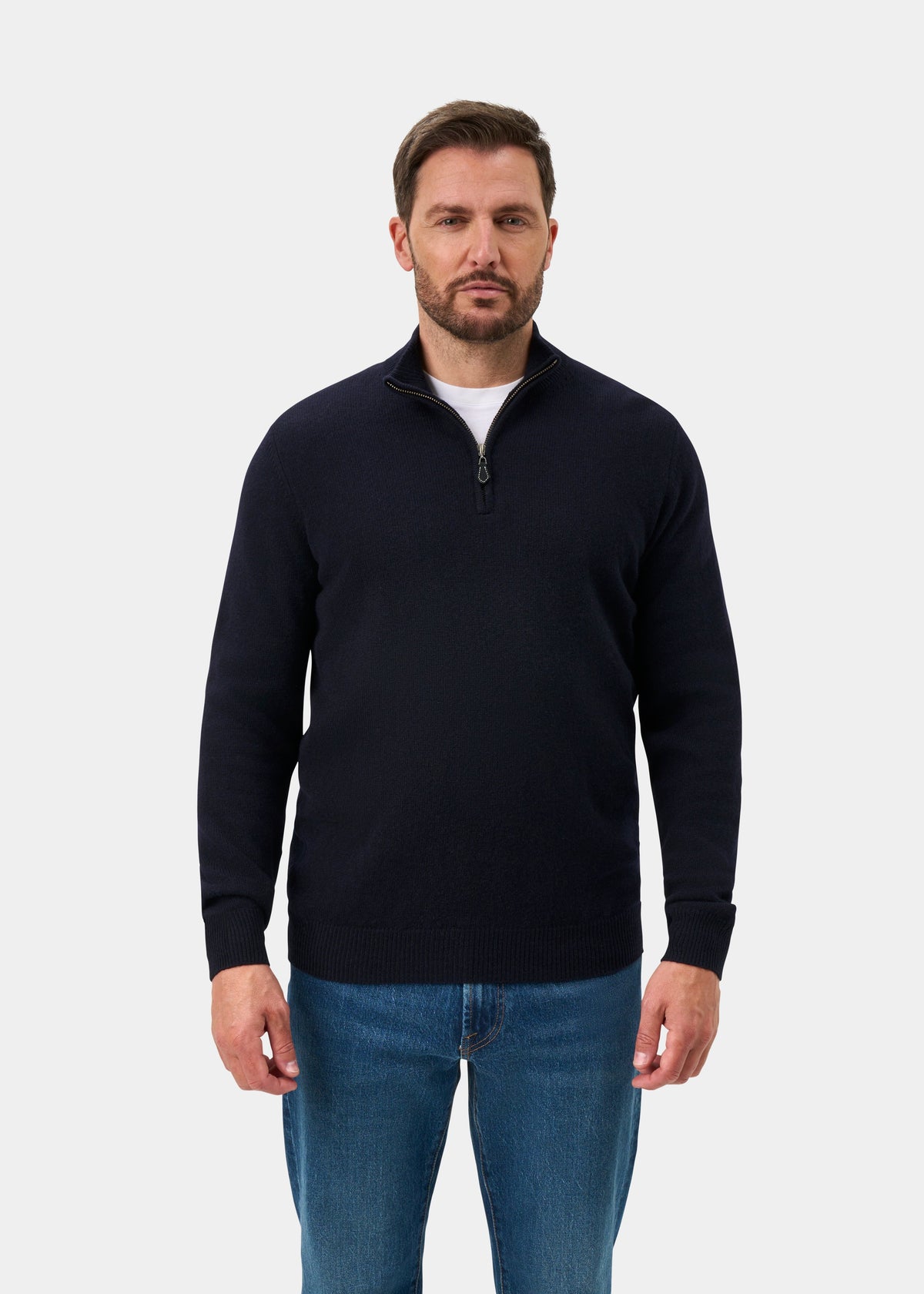 A man wearing a Sutherland Lambswool Quarter Zip Jumper In Navy over a white t-shirt and blue jeans.