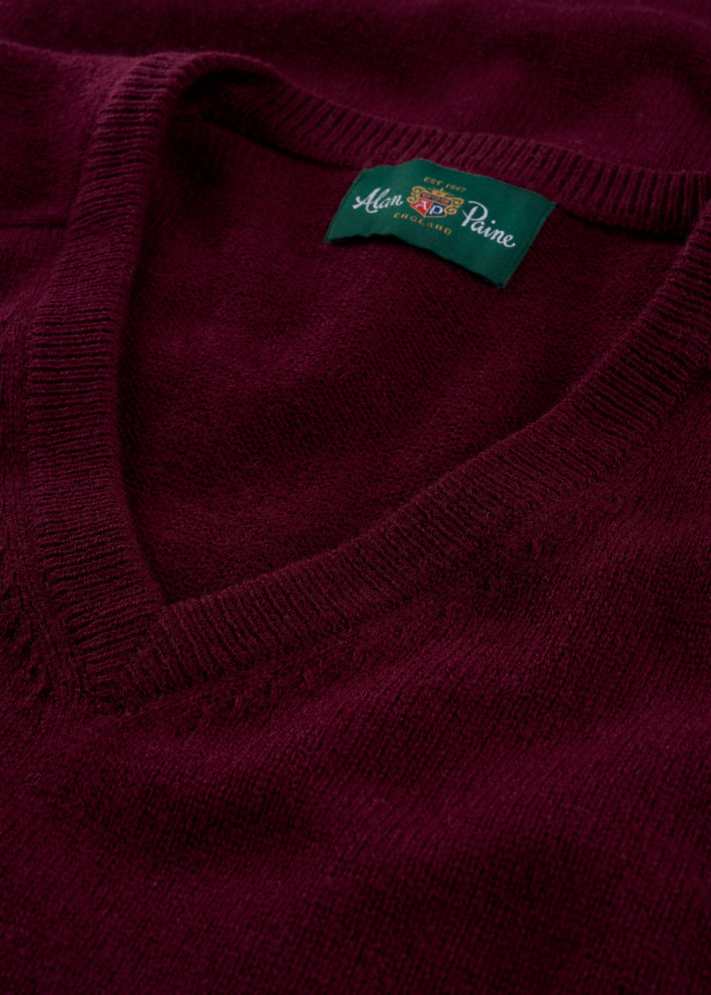 Close-up of the Kilsyth Lambswool V-Neck Jumper in Bordeaux, showing the Alan Paine label inside the collar.