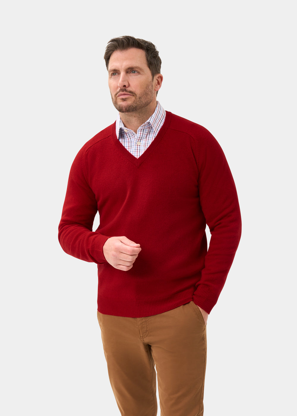 Man wears Hampshire Lambswool Vee Neck Jumper in Dubonnet, classic fit, with khaki pants against a plain background.