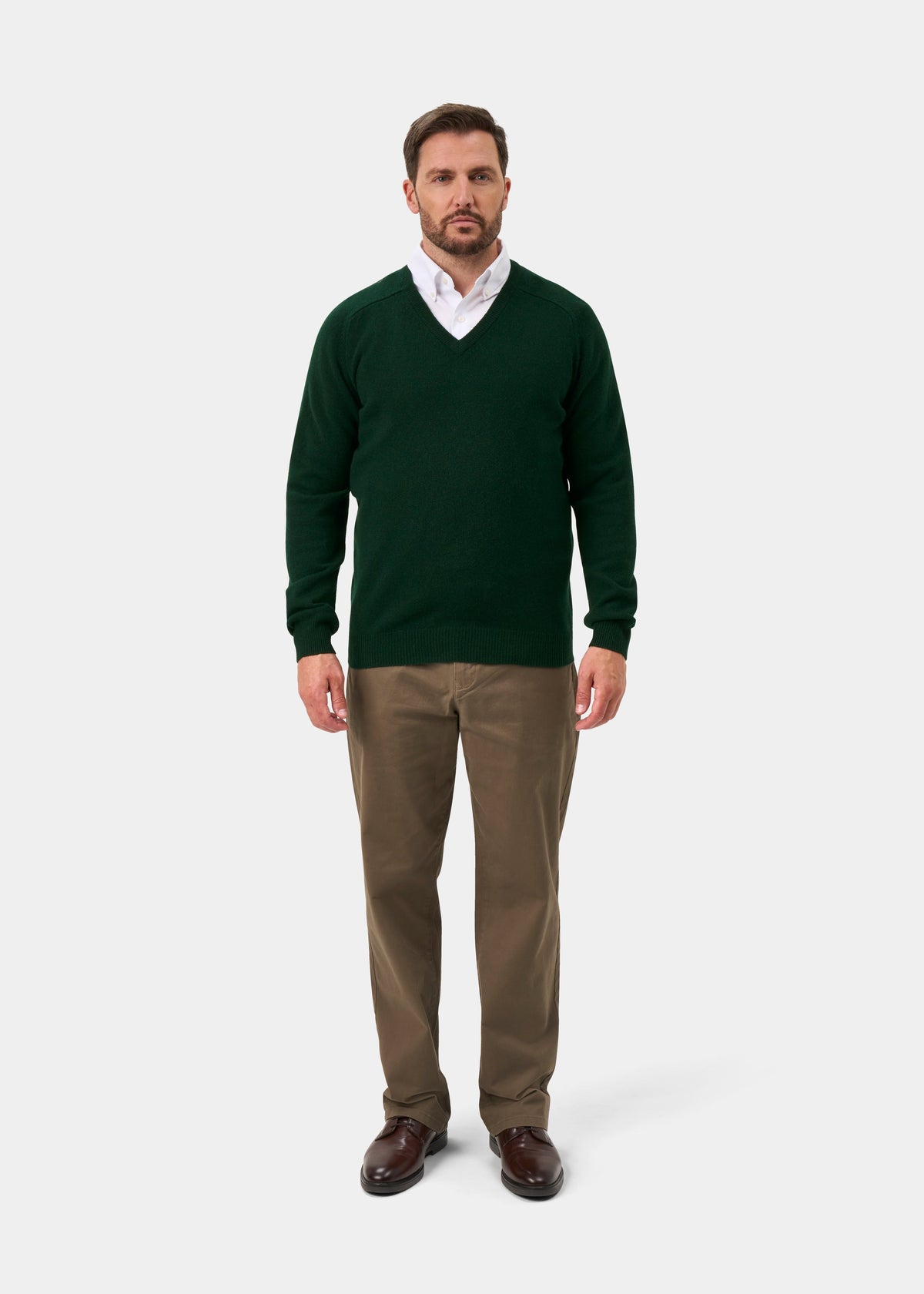 Man facing forward in Kilsyth Lambswool V-Neck Jumper in Tartan Green, white shirt, khakis, and brown shoes.