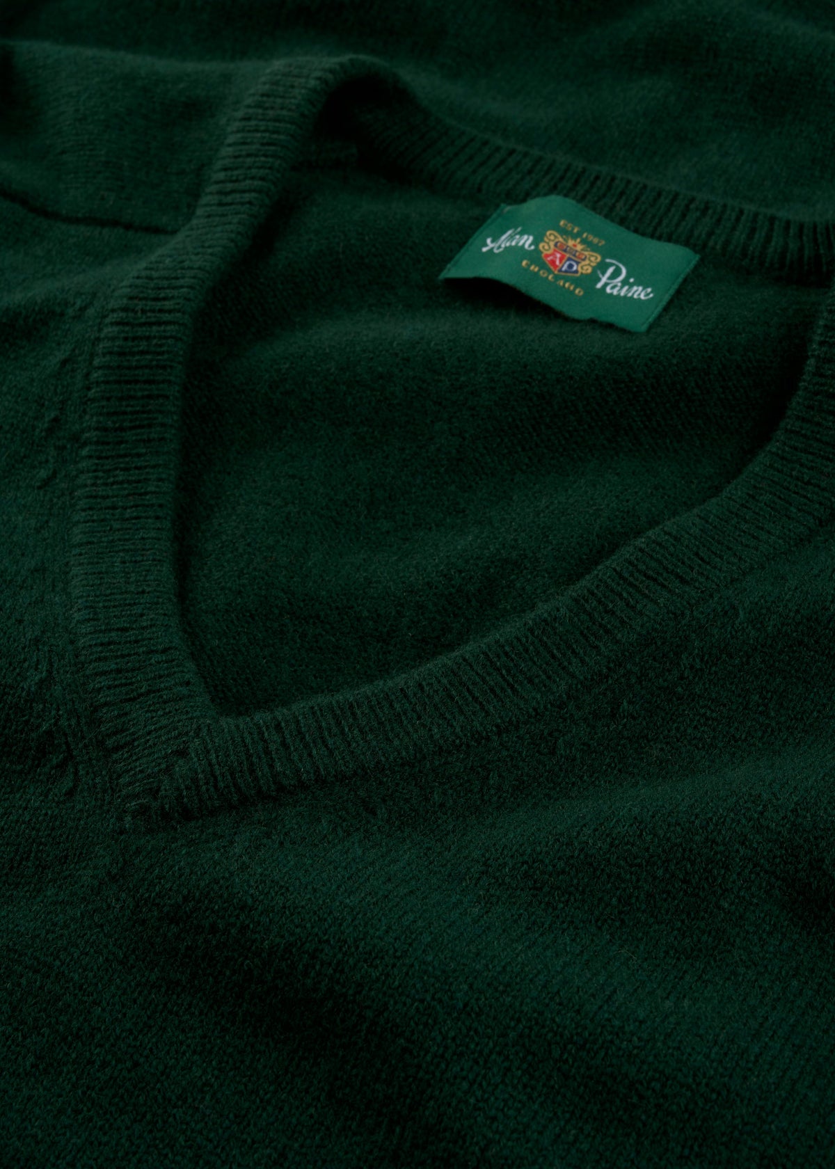 Close-up of the Hampshire Lambswool V-Neck Jumper in Tartan Green, classic fit, with label visible near collar.