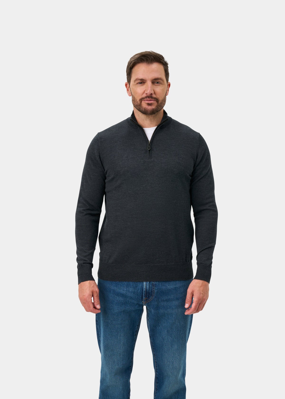 Man wearing the Barton Merino Wool Quarter Zip Jumper in Charcoal and blue jeans against a plain white background.