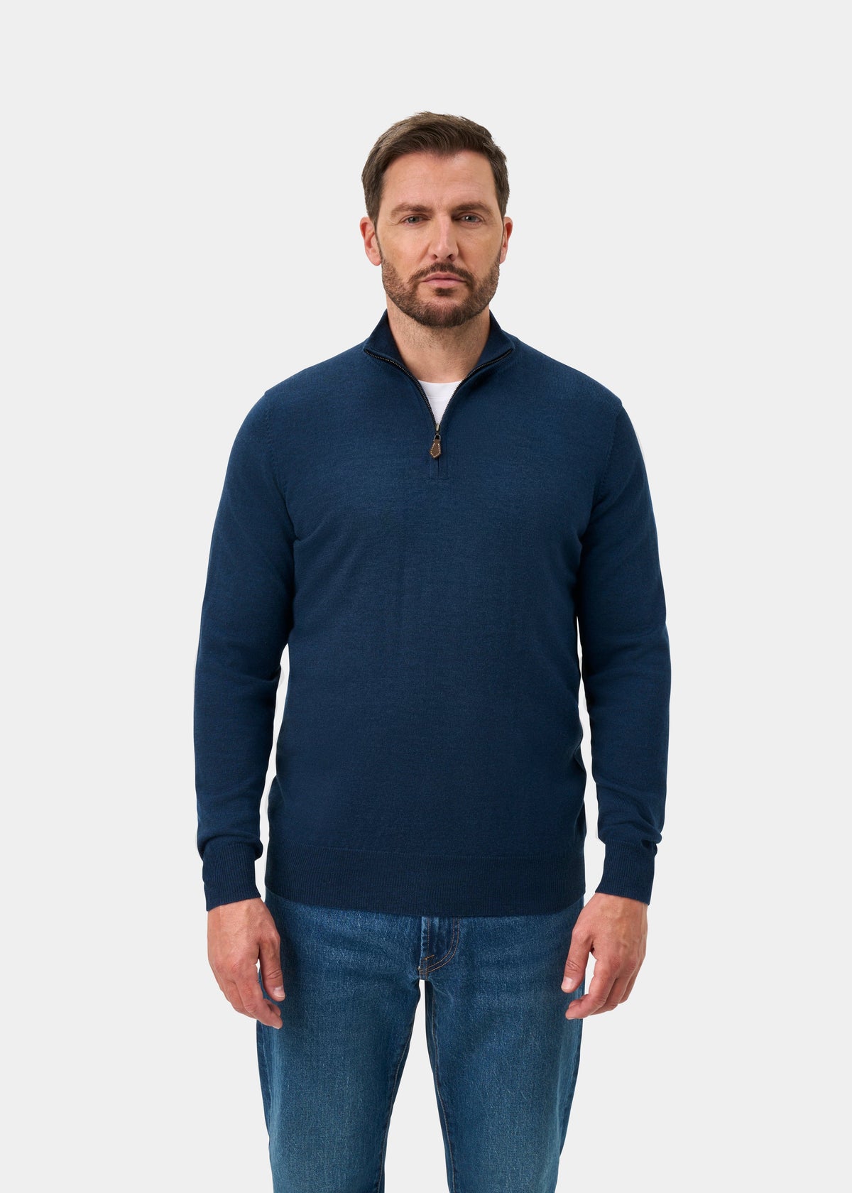 Man in Barton Merino Wool Quarter Zip Jumper in Indigo over a white shirt and blue jeans, plain background.