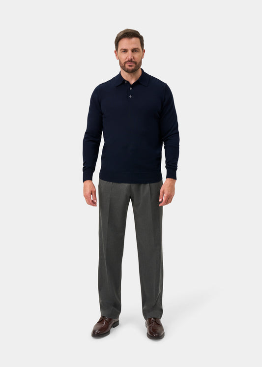 Man in Hindhead Merino Wool Polo Shirt, Dark Navy, regular fit, with gray dress pants and brown shoes on plain backdrop.