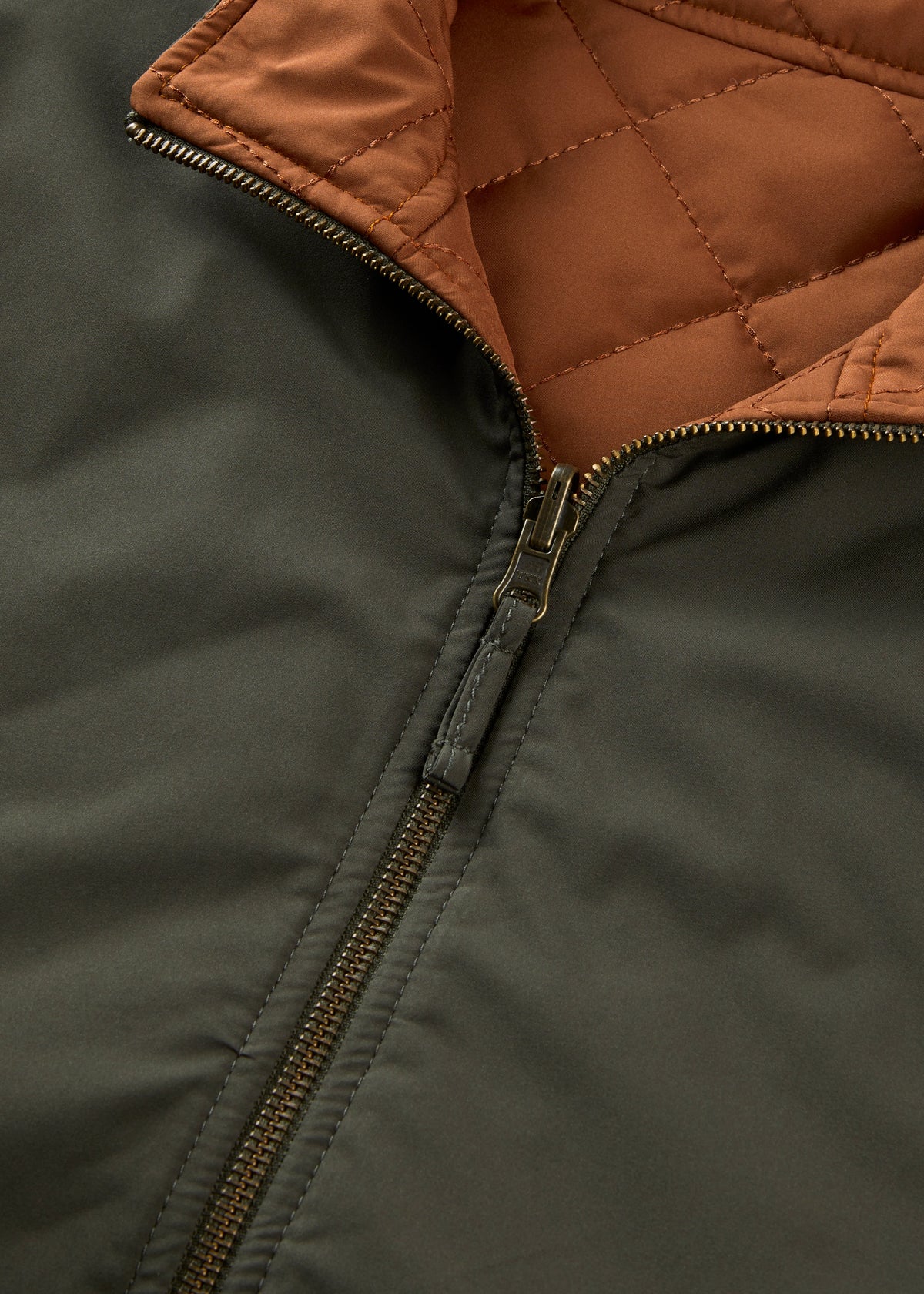 Close-up of the Swifthall Reversible City Gilet In Olive and Cider, showing an olive exterior and a quilted cider interior.