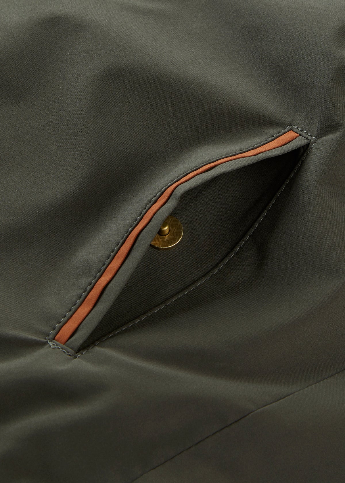 A Swifthall Reversible City Gilet In Olive and Cider pocket: olive green, water-resistant, rust trim, gold-tone snap.