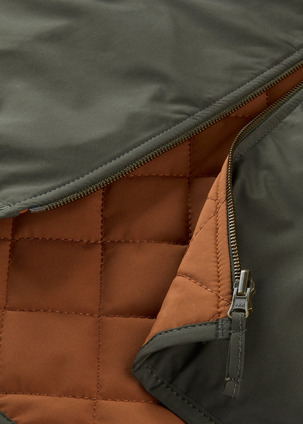 A partially zipped Swifthall Reversible City Gilet In Olive and Cider with an olive exterior and quilted cider interior.