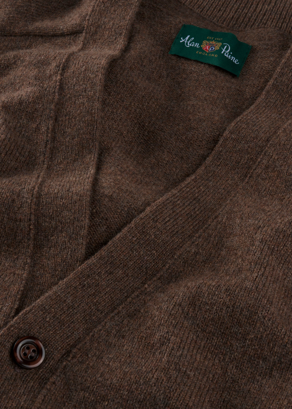 Close-up of Cornwall Lambswool V-Neck Cardigan in Tobacco, classic fit, with button detail and inside collar label visible.