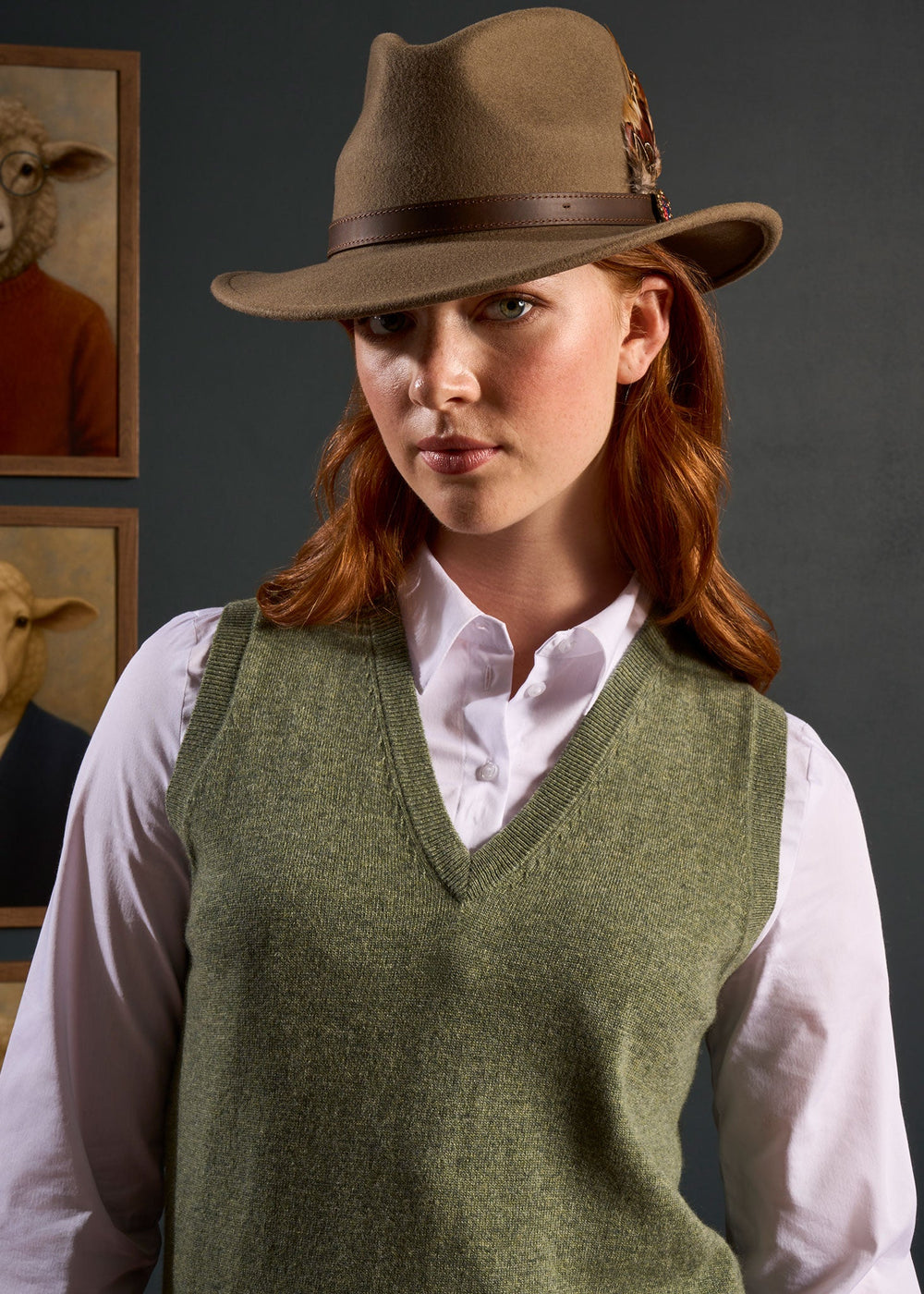 Woman in an Erin Wool & Cashmere V-Neck Slipover stands before framed artwork of sheep in clothes.