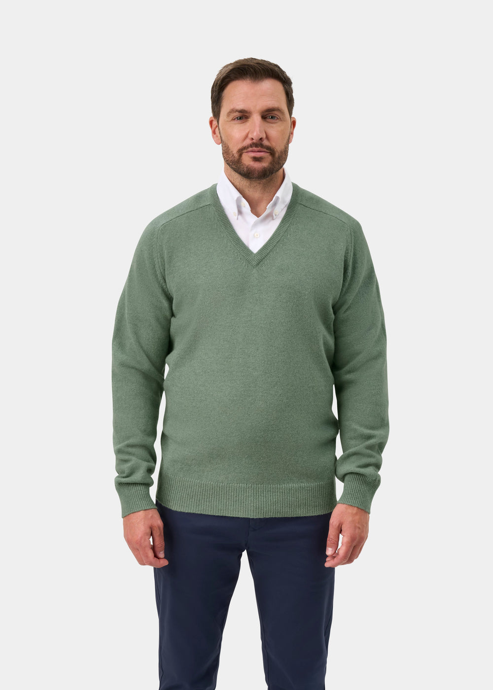 Man in a Hampshire Lambswool V-Neck Jumper in Mojito over a white shirt and navy pants, against plain background.