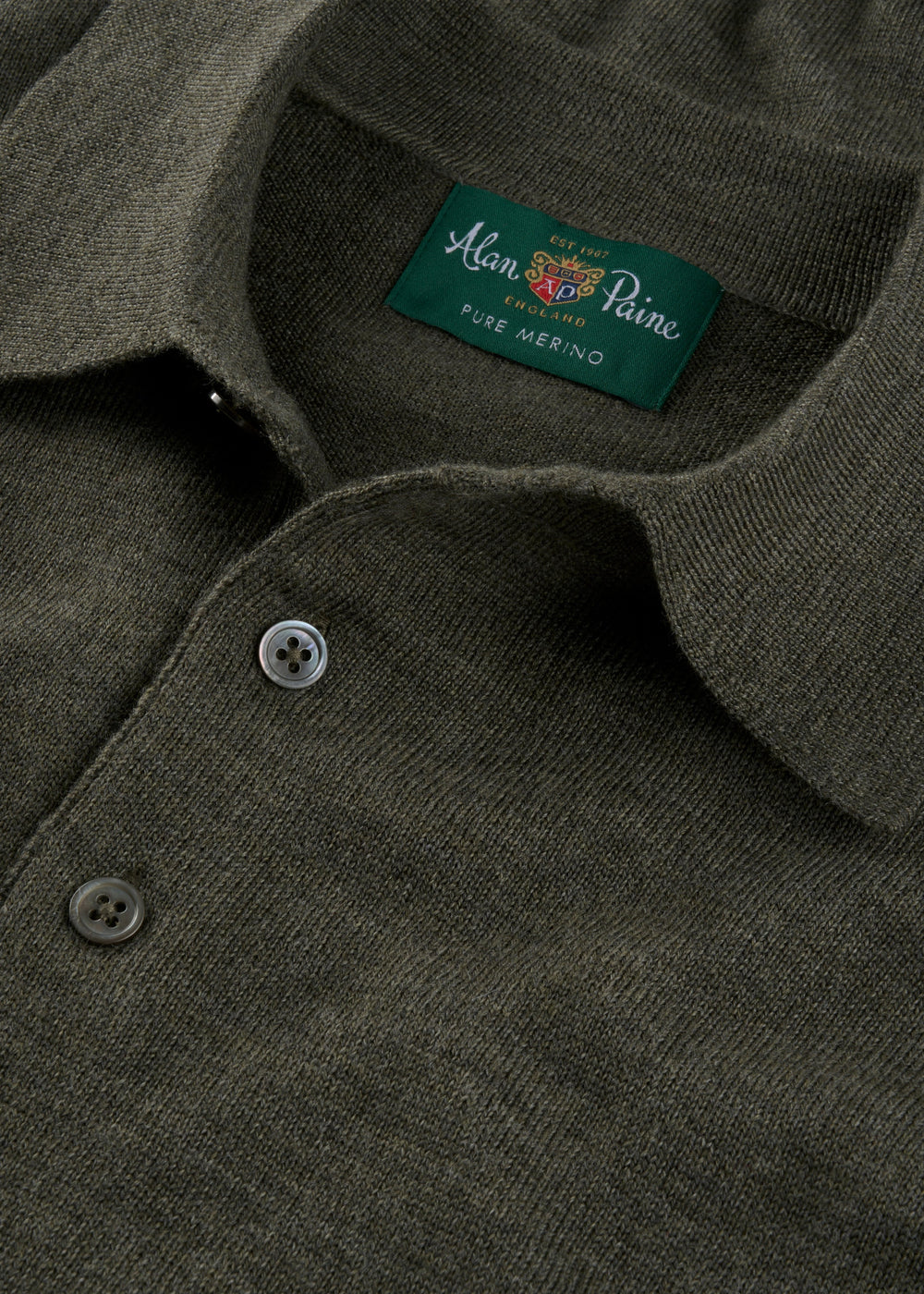 Close-up of a Hindhead Men’s Merino Wool Polo in Seaweed with buttons and visible collar branding.