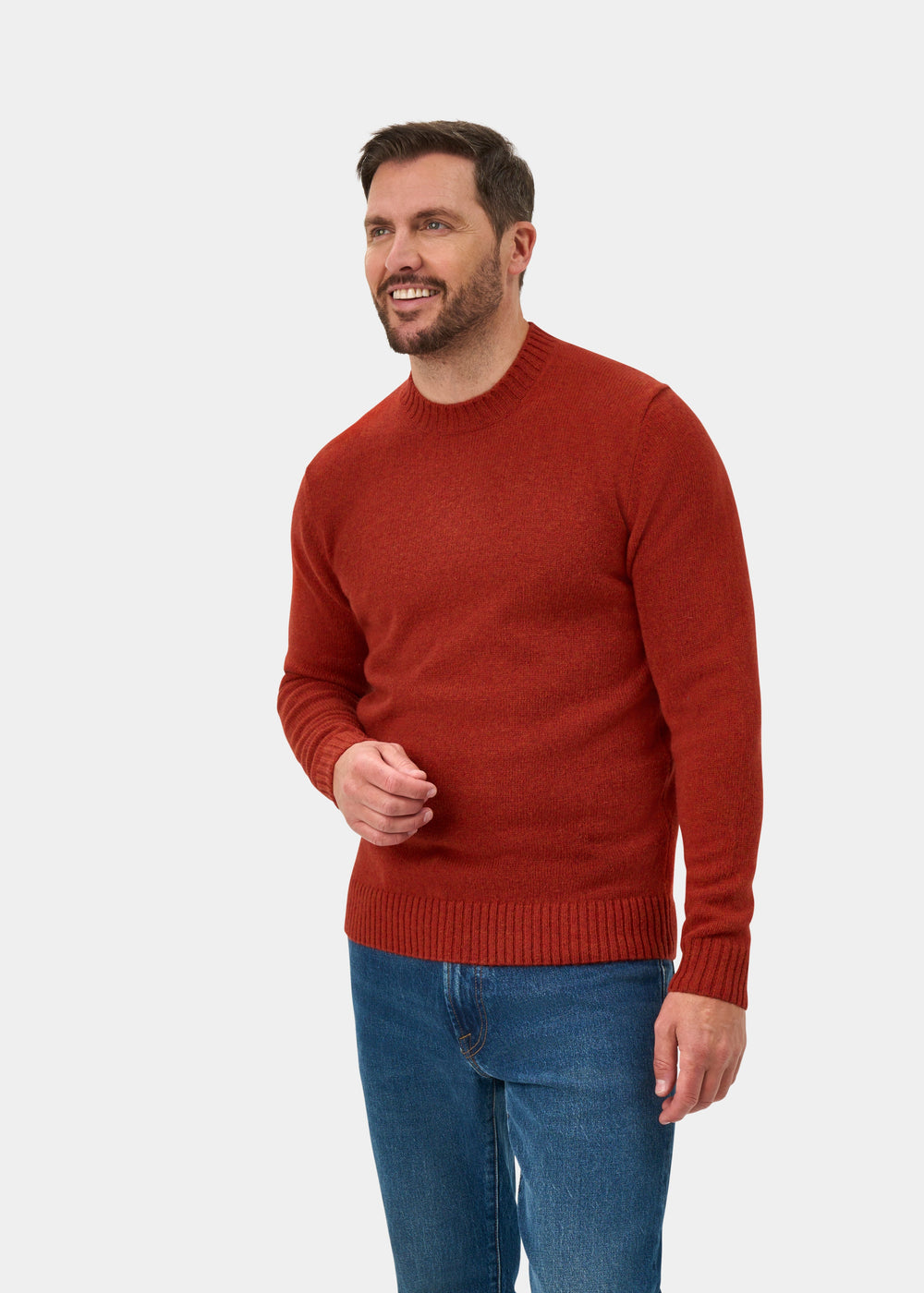 Smiling man in Kinnadie Supersoft Shetland Wool Crew Neck Jumper in Saffron, regular fit, and blue jeans on white.