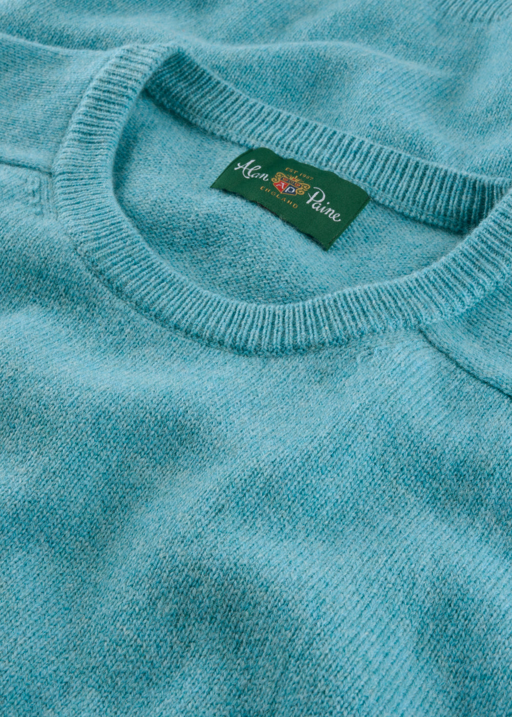 Close-up of a light blue sweater with a brand label on the collar.