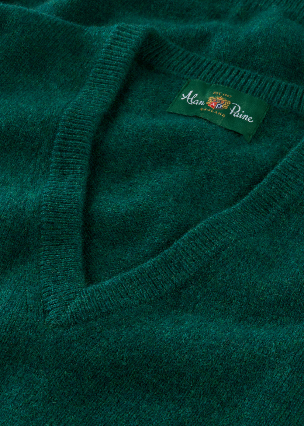 Close-up of a green sweater with a brand label on a matching background